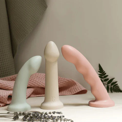 collection of dildos lying on pink fabric
