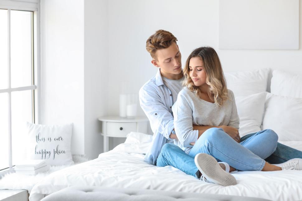 Couple relaxing on a bed with soft pastel beginner-friendly intimacy products from the Perfect Embrace collection.
